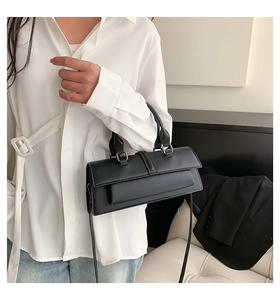 Minimalist black matte handbag featuring a structured top handle and slim shoulder strap
