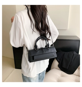 Minimalist black structured crossbody bag with top handle shown on model back view