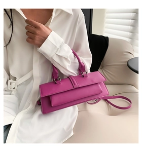 Detail of a chic magenta rectangular leather handbag featuring a smooth finish and buckle