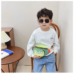 Close-up of child wearing green and yellow crossbody bag with Play lettering in home setting