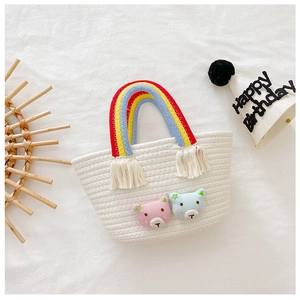 Détail du panier tressé blanc avec poignée arc-en-ciel, franges et écussons d'ours