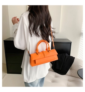 Rear view of model wearing the orange leather handbag as a crossbody fashion accessory