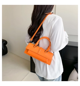 Detail of vibrant orange leather shoulder bag with circular top handle and metallic buckle