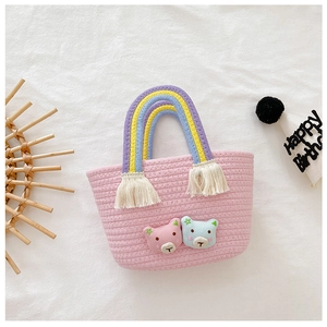 Vue détaillée du sac panier rose tressé avec anses arc-en-ciel et écussons d'ours