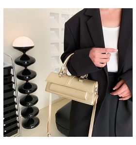 Detail view of the beige champagne faux leather handbag worn on shoulder with suit