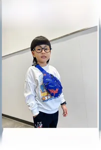 Dettaglio del marsupio blu per bambini con dinosauro cartone animato e veicolo da lavoro