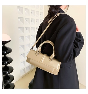 Detail of champagne gold handbag with shoulder strap worn by model in black blazer
