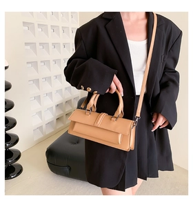 Close-up of a structured camel handbag with top handle and fine textured leather detail