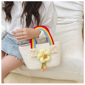 Détail du sac tressé enfant avec anse arc-en-ciel et grande fleur jaune décorative