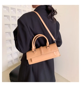 Detail of camel leather baguette bag showing sleek flap closure and slender shoulder strap
