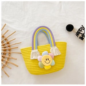Détail du sac tressé jaune pour enfant avec anse arc-en-ciel et fleur de soleil en peluche
