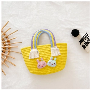 Panier tressé jaune avec poignées arc-en-ciel à pompons et écussons lapins en détail