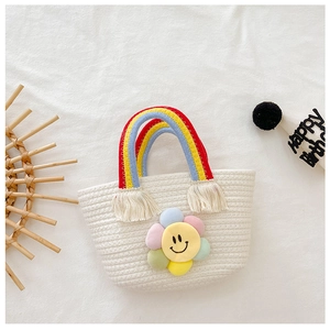 Détail du sac tressé avec poignée à pompon arc-en-ciel et ornement de tournesol en peluche