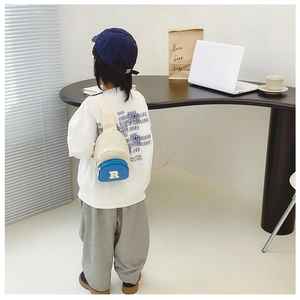 Toddler nylon chest bag with white R patch and blue zip pocket detail on a child