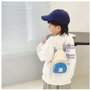 Detail view of the contrast color kid's chest bag with embroidered R patch on shoulder