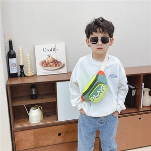 Kids colorful crossbody chest bag with Play print on a boy model in a minimalist room