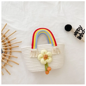 Détail d'un sac tressé enfant avec fleur 3D et poignées aux rayures arc-en-ciel