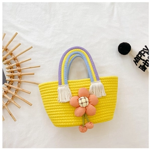 Détail d'un sac tressé jaune pour enfant avec anse arc-en-ciel et grande fleur orange