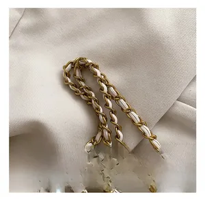 Detail of elegant gold chain strap with white leather weave and pearl accents on kids bag