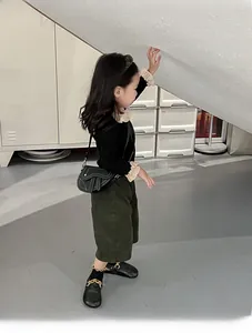 Détail d'un petit sac de selle noir en cuir avec une tenue d'automne pour fille