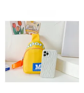 Gelbe Kinder-Brusttasche mit M-Buchstaben-Logo neben einem Smartphone für den Größenvergleich