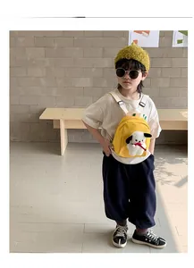 Toddler wearing a bright yellow canvas backpack featuring a cute 3D plush puppy with a red bowtie