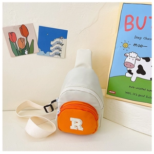 Detail of child's nylon crossbody bag with orange pocket and white letter R embroidery patch