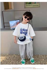 Détail d'une tenue d'été garçon avec t-shirt blanc à logo et pantalon gris à rayures
