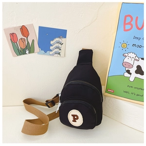 Detail view of black canvas kids chest bag with P letter patch and brown adjustable strap