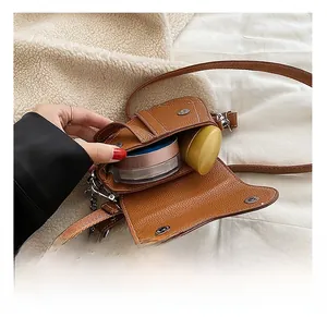 Vue intérieure d'un sac bandoulière en cuir marron avec rouge à lèvres et maquillage