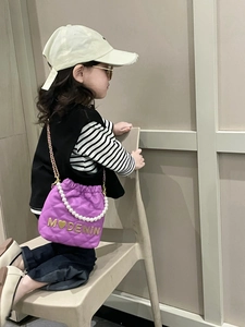Detail of purple quilted girls bucket bag with pearl handle and golden hardware