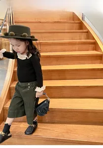 Gros plan d'un sac selle en similicuir noir avec une tenue en velours pour fille