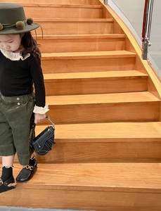 Détail d'un mini sac selle en cuir noir porté avec une tenue d'automne fille