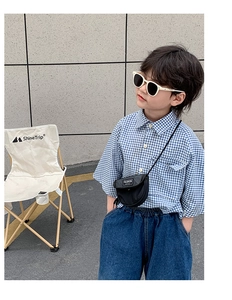 Sac bandoulière enfant en toile noire porté avec une chemise à carreaux et un jean