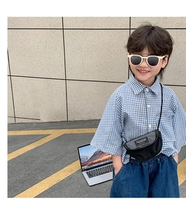 Détail d'un sac bandoulière demi-lune en nylon noir pour enfant avec patch de mode