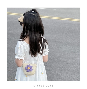 Détail d'un sac seau en paille tissée pour filles avec une fleur violette en relief