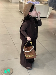 Detail of child's brown quilted bucket bag with pearl handle and gold MODENIN logo