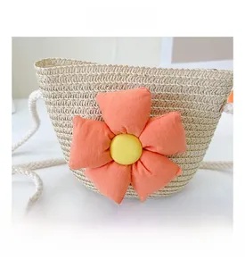 Détail du sac en paille pour enfants avec fleur en tissu orange et bandoulière en coton