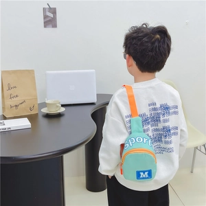 Kinder-Brusttasche mit M-Print und orangefarbenem Gurt in Mintgrün am Jungen-Model