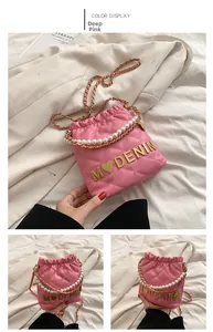Detail of dark pink quilted bucket bag with pearl handle and golden chain strap