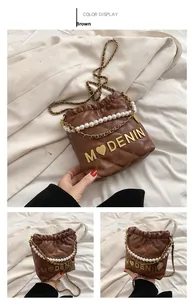 Close-up of brown quilted bucket bag with pearl handle and golden chain strap detail