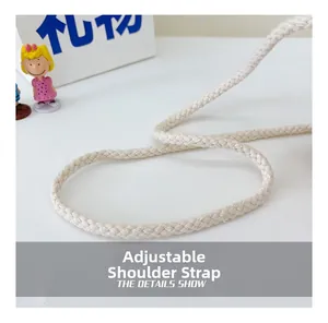 Détail de la bandoulière tressée réglable en crème pour sac en paille enfant