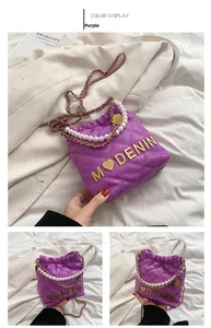 Detail of purple quilted girl purse with pearl handle and golden letter M logo