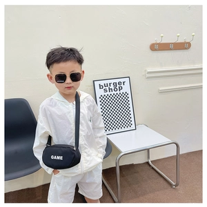 Close-up of black canvas crossbody bag with white GAME text on a child outfit