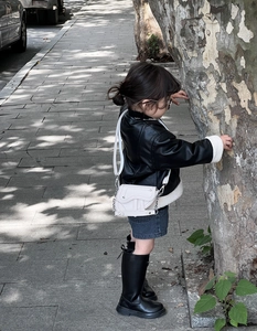 Photo en extérieur d'un sac selle blanc en similicuir pour fille avec une chaîne argentée