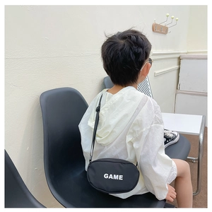Detailed back view of a child wearing a black canvas crossbody bag with white GAME print