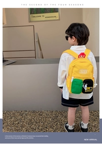 Detail view of child model wearing yellow backpack with colorful pockets and lovely logo