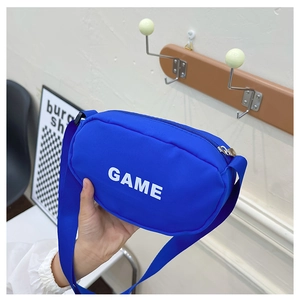 Detail of royal blue nylon crossbody bag featuring white GAME lettering and adjustable strap