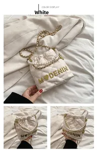 Detail view of cream quilted bucket bag with pearl chain and gold heart embellishments