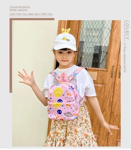 Pink toddler backpack with cartoon space prints shown on a child model indoors